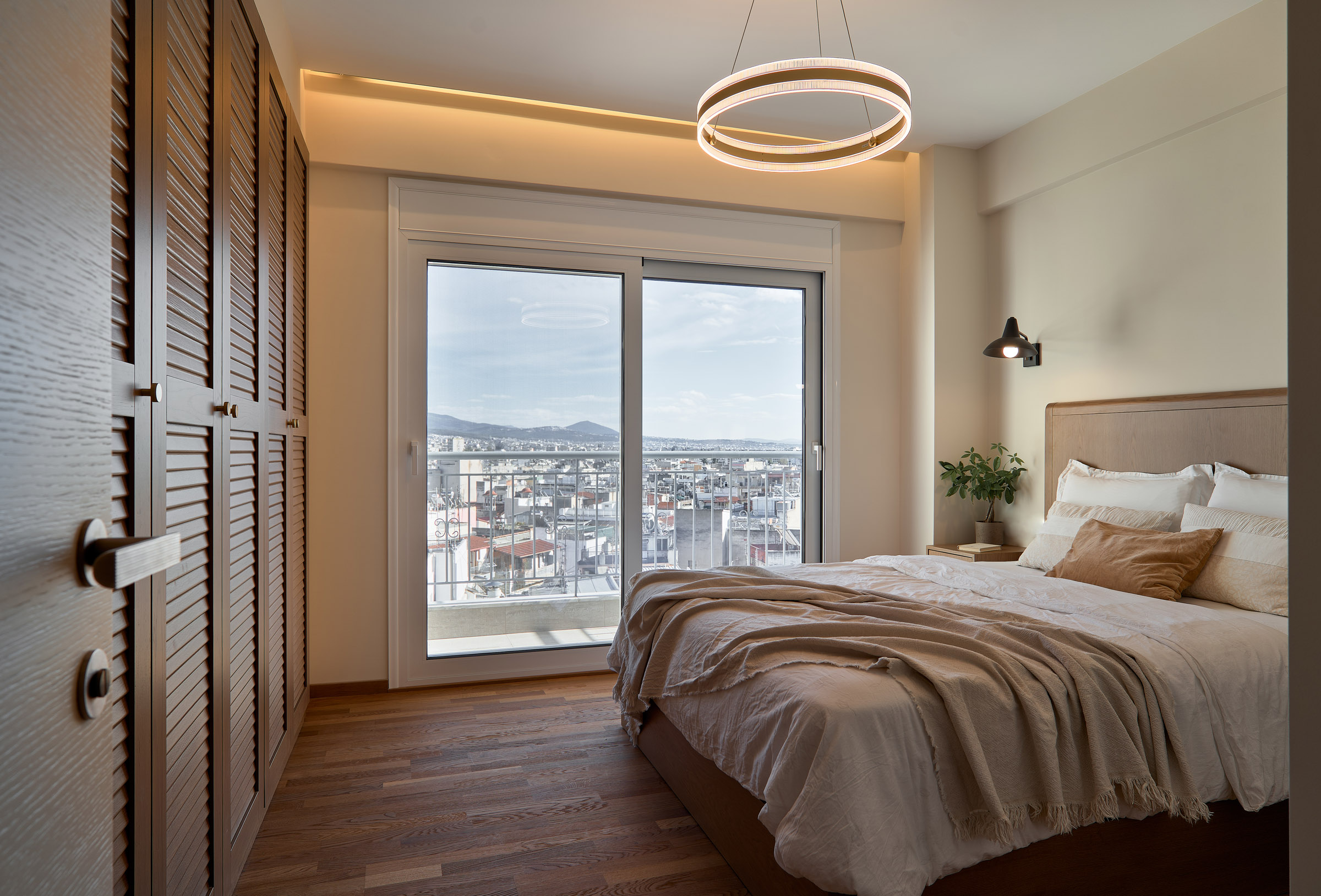 Bedroom of a renovated apartment in Thessaloniki with large openings and city view -