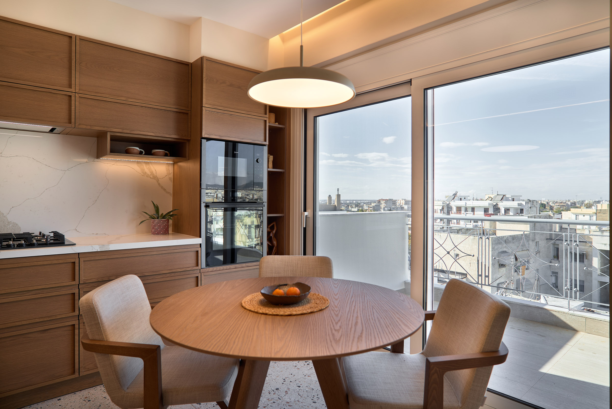 Kitchen and dining room of a renovated apartment in Thessaloniki with large openings and city view