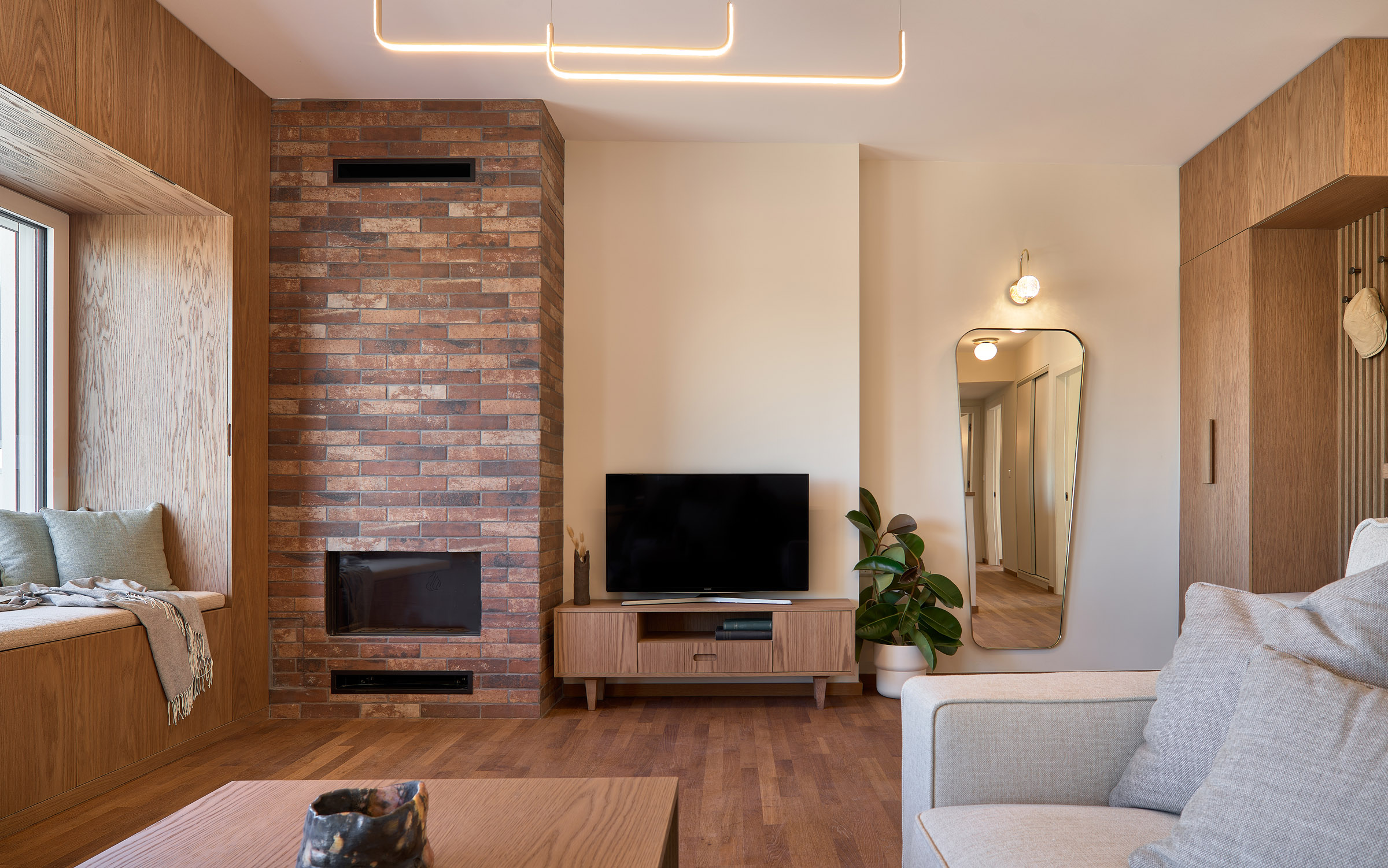 Living room of a renovated apartment in Thessaloniki with large openings, fireplace and window seat