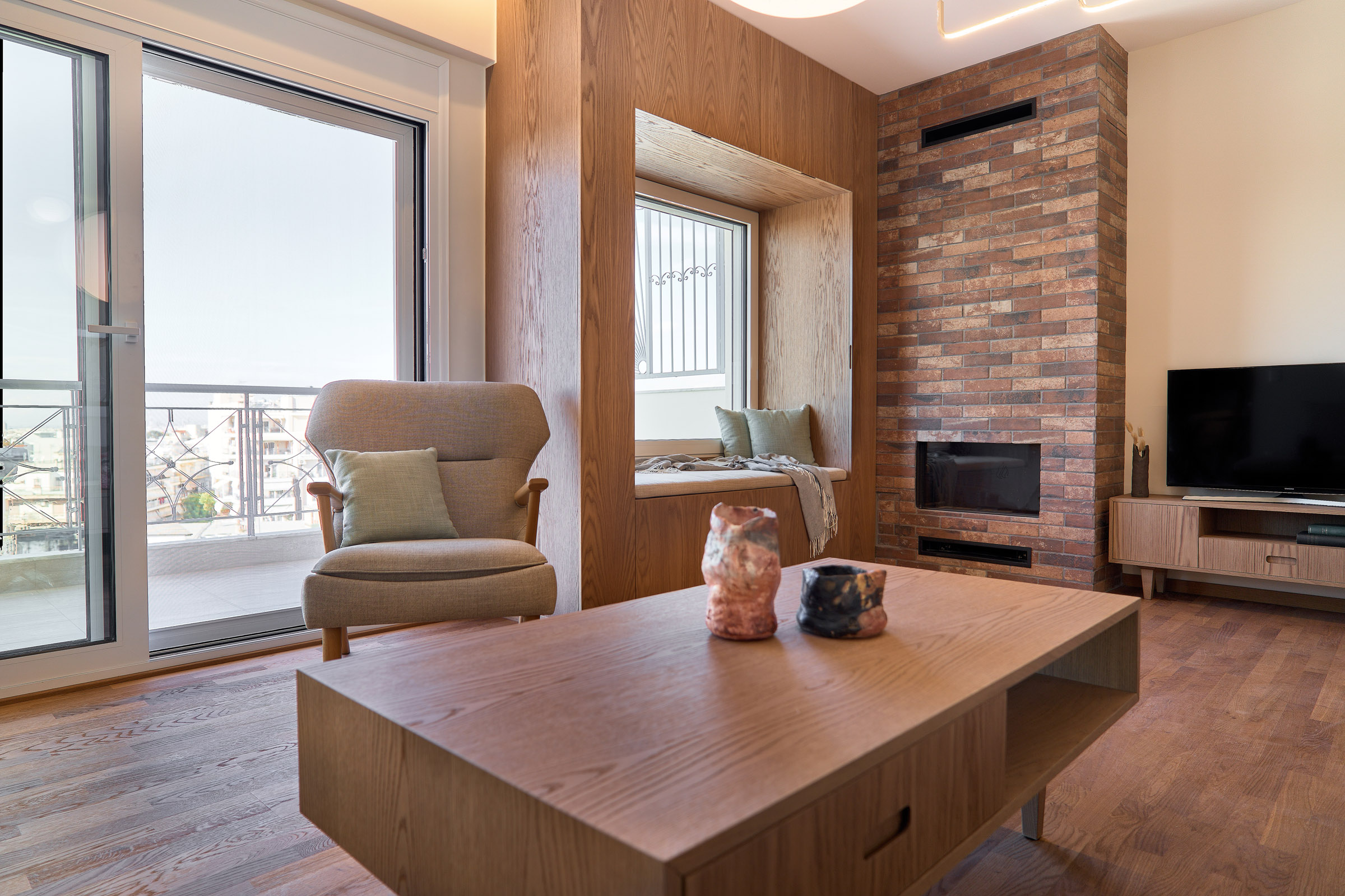 Living room of a renovated apartment in Thessaloniki with large openings, fireplace and window seat - city view