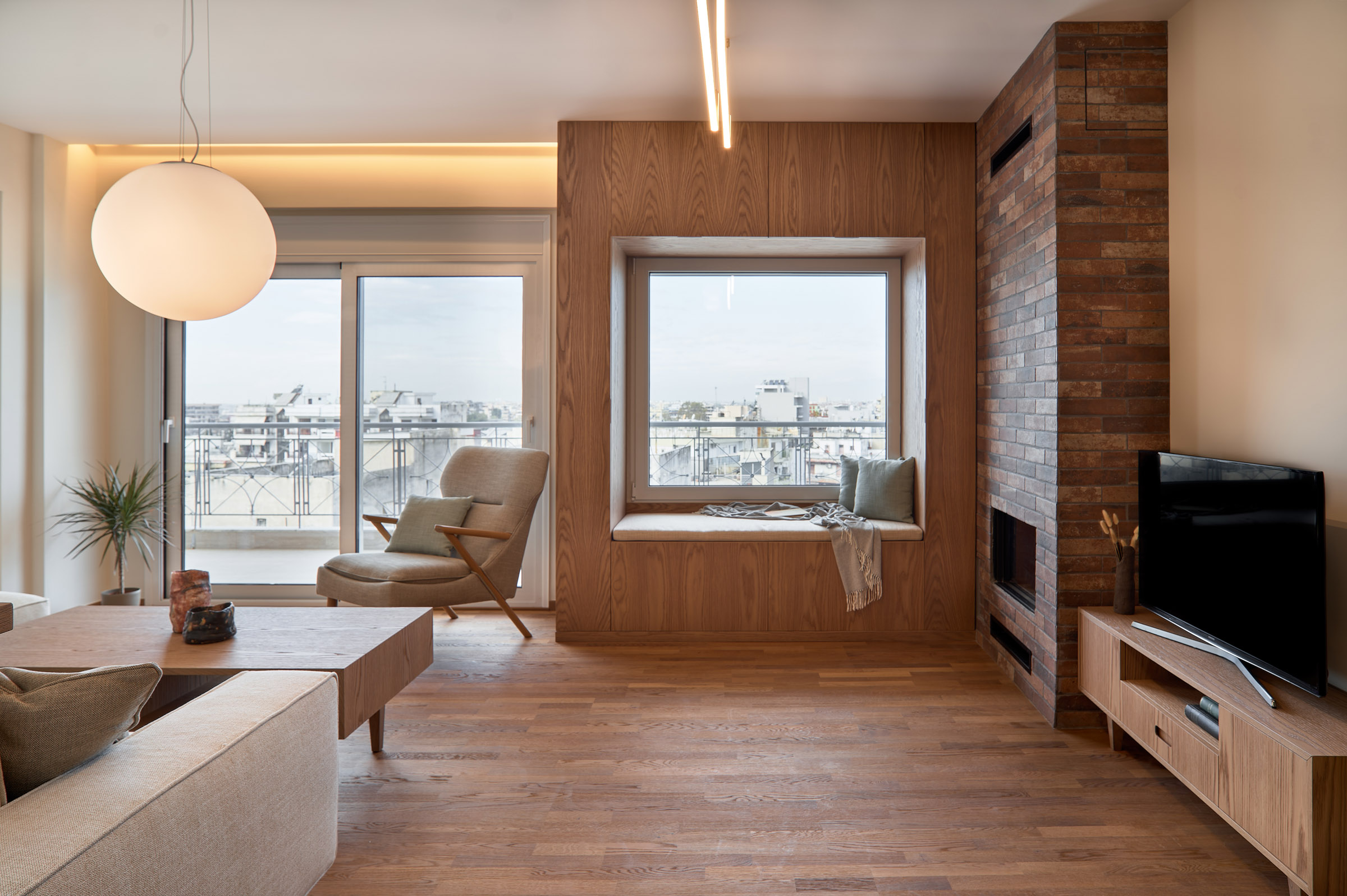 Living room of a renovated apartment in Thessaloniki with large openings, fireplace and window seat - city view