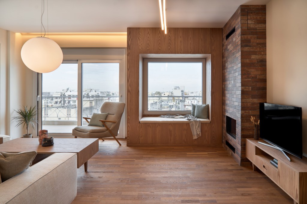 Living room of a renovated apartment in Thessaloniki with large openings, fireplace and window seat - city view