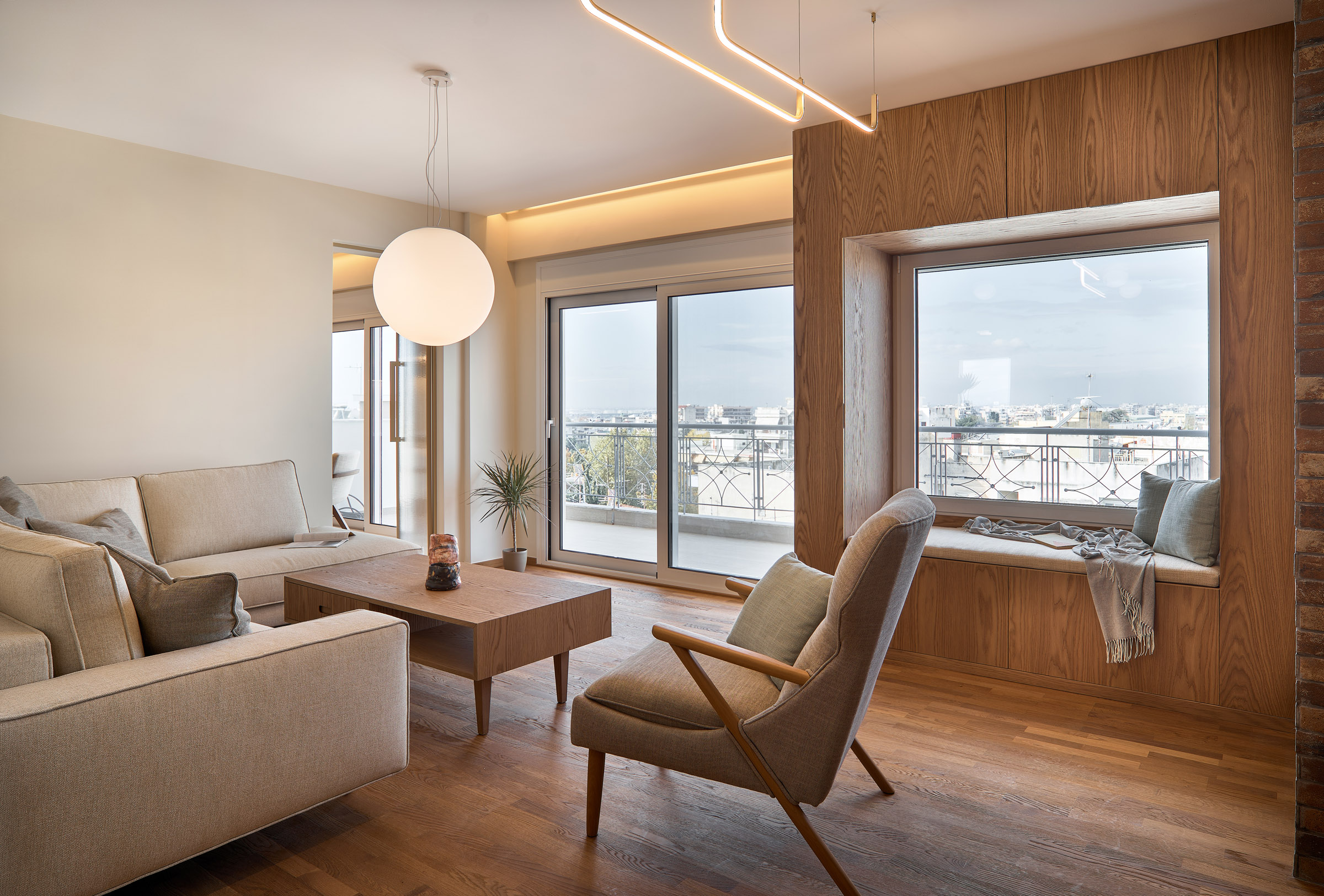 Living room of a renovated apartment in Thessaloniki with large openings, and window seat - city view