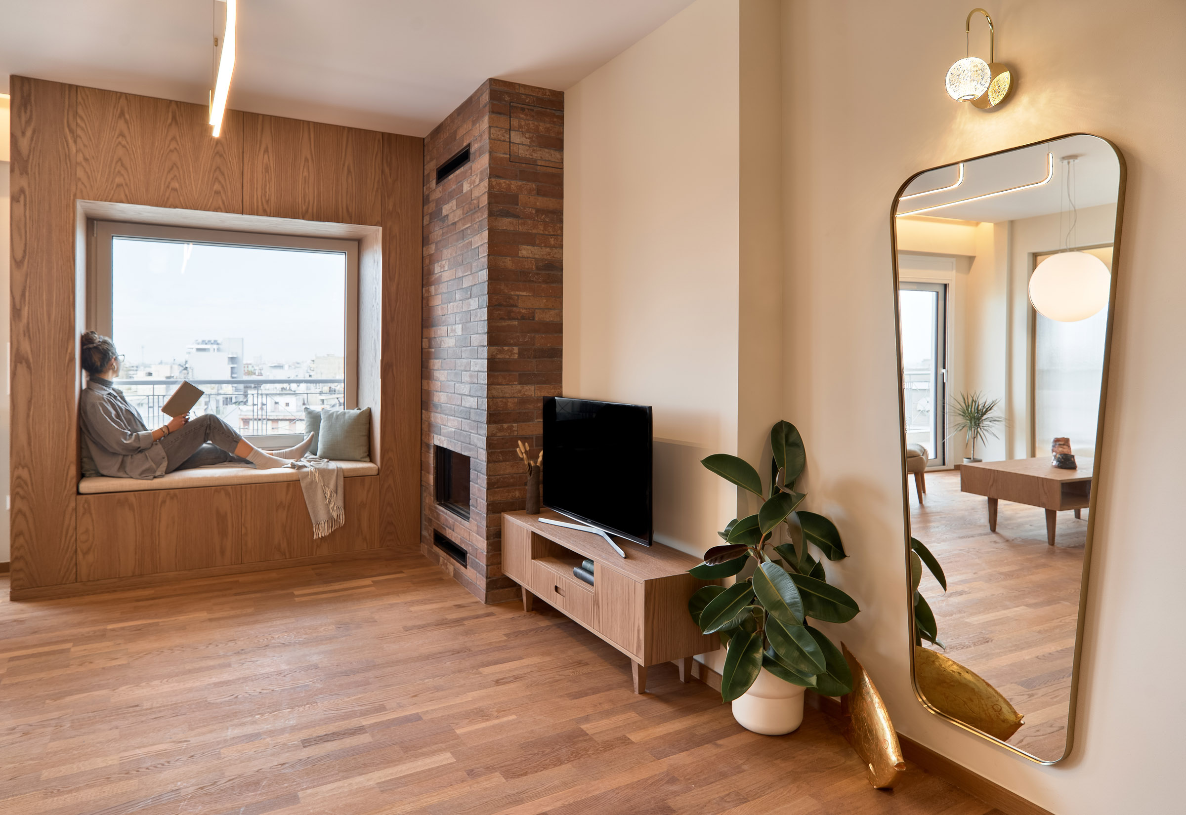 Living room of a renovated apartment in Thessaloniki with large openings, fireplace and window seat