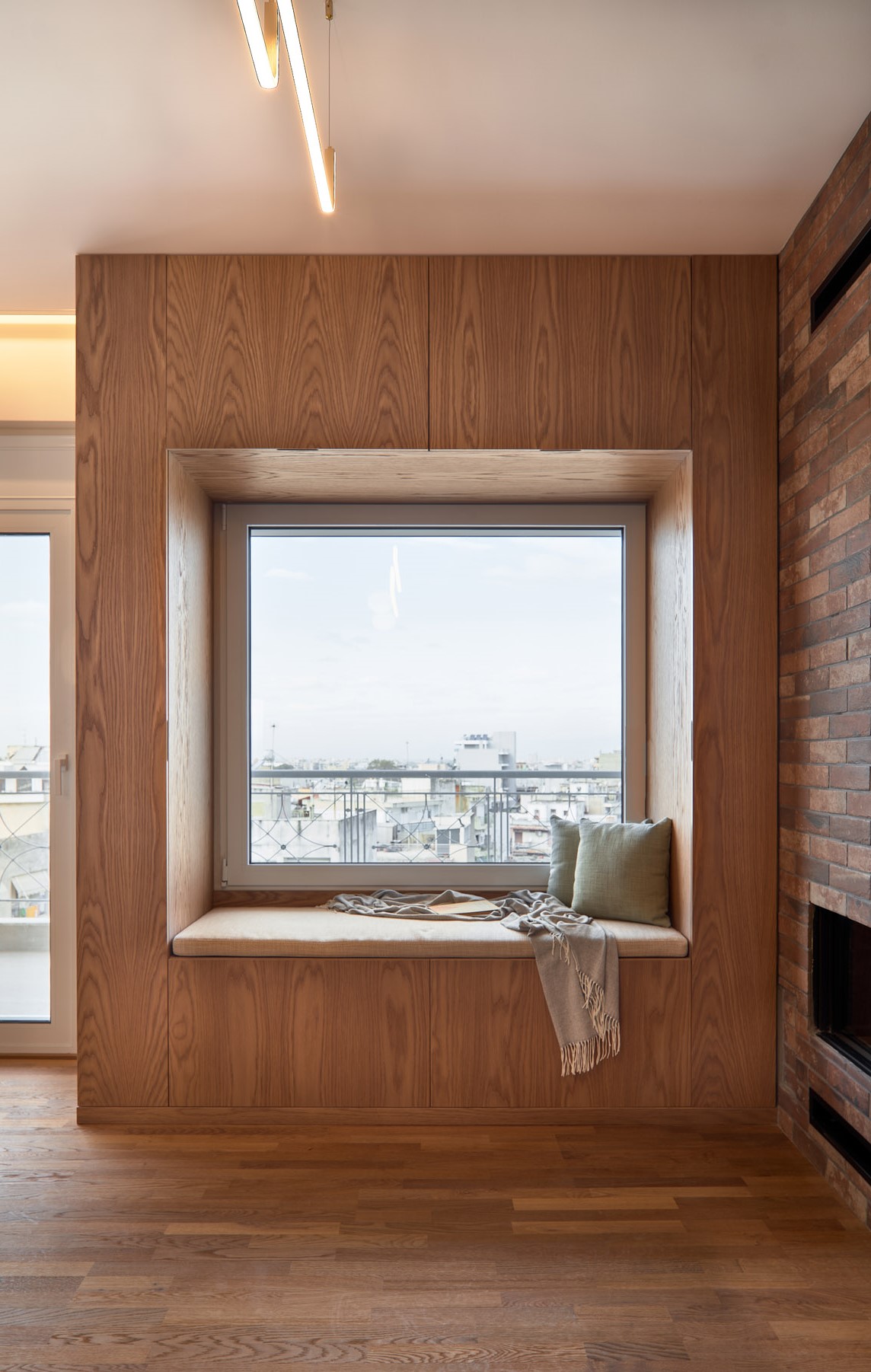 Living room of a renovated apartment in Thessaloniki with large openings, fireplace and window seat
